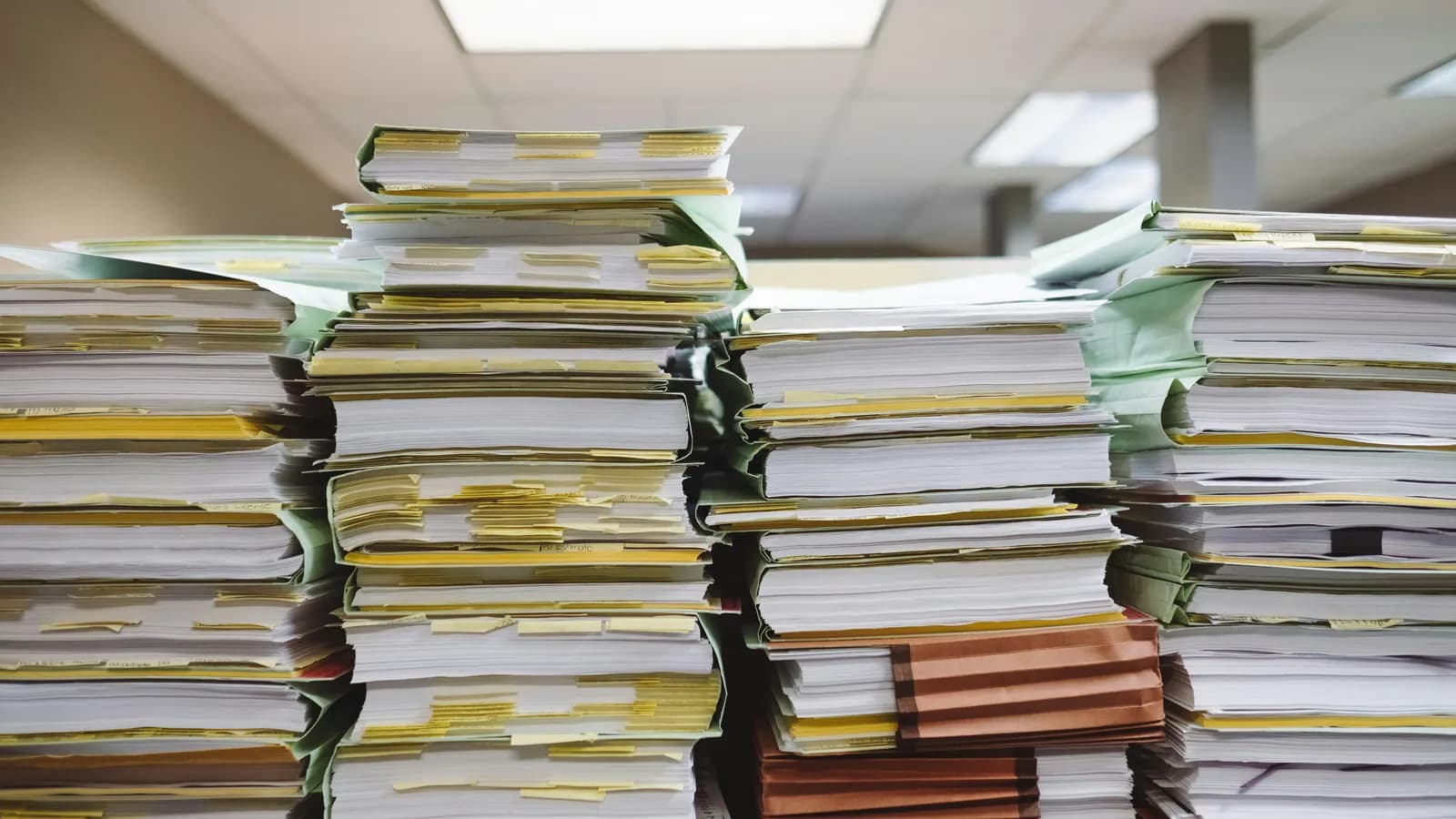 Piles de dossiers papier et de chemises dans un bureau