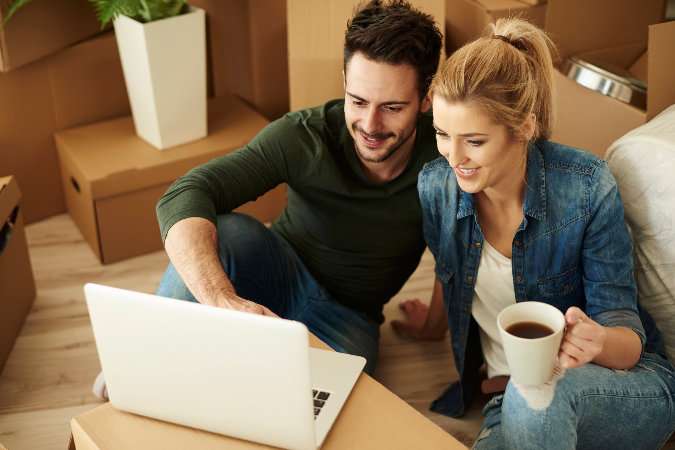 Couple préparant un déménagement avec ordinateur portable